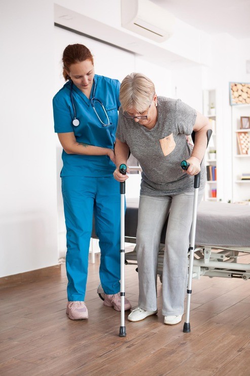 Nurse helping a patient walk with crutches